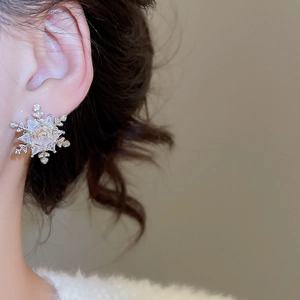 Close-up of a model wearing a snowflake stud earring with sparkling cubic zirconia