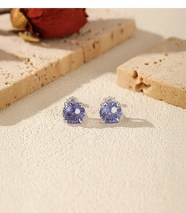 Macro shot of purple round zircon earrings with silver four-prong setting and fine cut