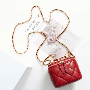 Detailed top view of red quilted cylinder bag with metal chain strap on fashion magazine