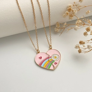 Close-up of pink heart-shaped puzzle necklace with rainbow enamel pattern and gold chain
