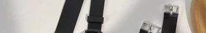 Macro view of black silicone watch straps with silver metal buckles on white background