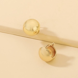 Detailed close-up of polished golden spherical earrings featuring a sleek mirror finish