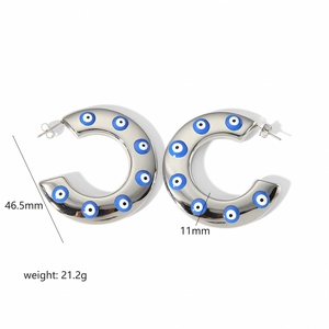 Detail view of silver C-shaped steel hoop earrings with blue eye patterns and size specs