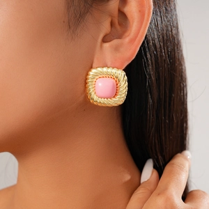 Close-up of vintage geometric gold earrings featuring square pink gemstones on model