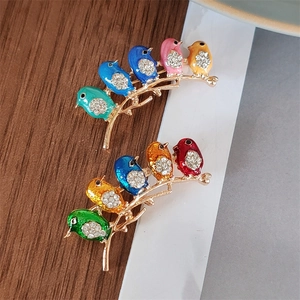 Close-up of colorful enamel bird brooches with rhinestones on a golden branch base