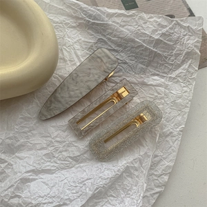 Close-up of marble pattern and glitter hair clips with gold metal base for styling