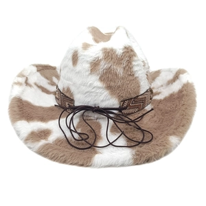 Detail of plush cow print cowboy hat featuring woven ethnic band and decorative tassel strings