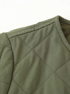 Detailed macro view of diamond quilted pattern and bound neckline on army green jacket
