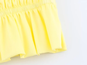 Detailed close-up of yellow halter top featuring elastic ruched waist and twill fabric texture
