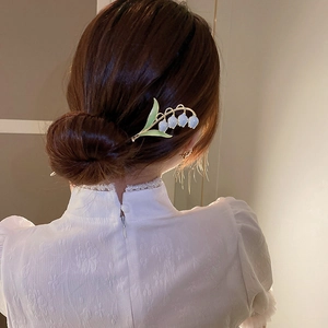 Épingle à cheveux élégante muguet avec fleurs bleues et feuilles vertes sur chignon
