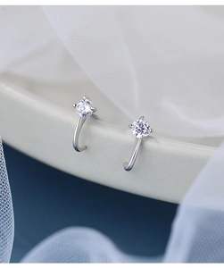 Macro view of S925 silver curved stud earrings with brilliant prong-set cubic zirconia