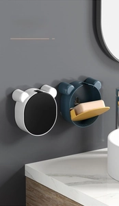Detail of wall-mounted cartoon bear soap holder with drainage and flip lid design
