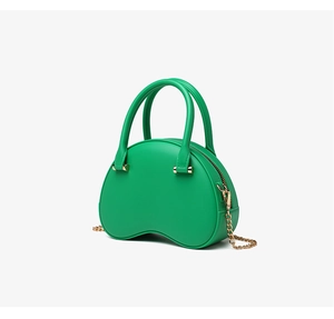 Detail of green jelly cloud bag with gold chain strap and top handle on white background