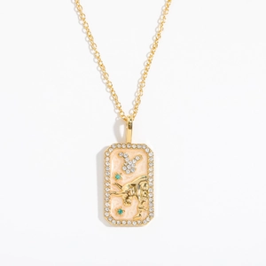 Detailed close-up of golden zodiac pendant with sparkling rhinestones and green gemstones