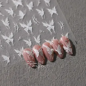Detail of 3D embossed white butterfly nail stickers on sparkling pink fake nails