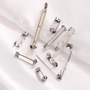 Stainless steel brooch pins with safety locks in various sizes on white silk background