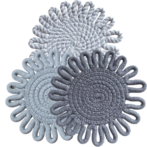 Three grey flower-shaped woven cotton coasters in light, medium, and dark tones
