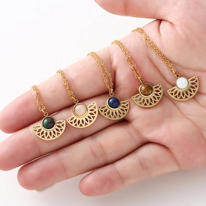 Close-up of fan-shaped gold pendants inlaid with natural stones held in hand