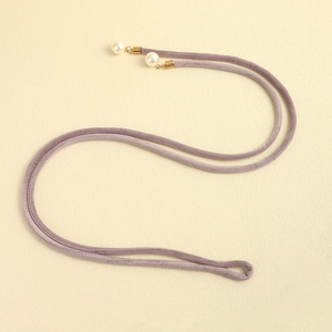 Close-up of lavender velvet decorative belt with golden metal ends and white pearl charms