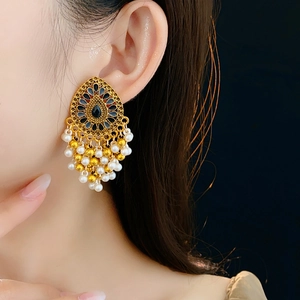 Détail de boucles d'oreilles vintage avec pierres bleues et pompons en perles sur mannequin