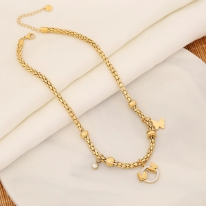 Detail of gold-plated woven chain necklace with butterfly pendants and crystal beads
