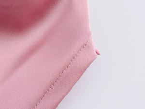 Vue macro de la texture du satin rose et des coutures précises sur le pantalon large