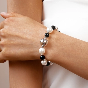 Detail of beaded bracelet with black beads, white pearls and silver metal accents on wrist