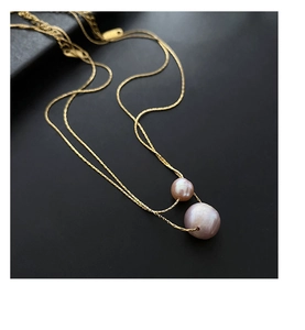 Macro shot of double natural pearls on a gold twisted rope chain over dark background