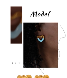 Detail of twisted heart earrings with sky blue enamel and golden metal finish on model