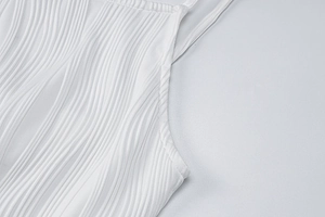 Close-up of white dress showing elegant 3D wave texture and slim shoulder straps