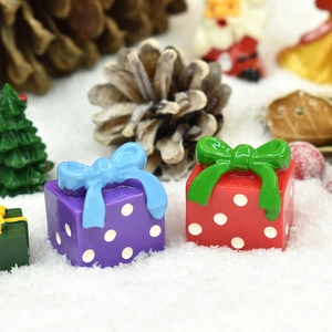 Miniature resin Christmas gift boxes with bows on artificial snow festive background