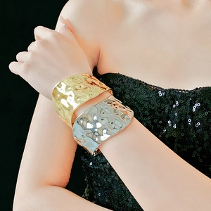 Détail d'un large bracelet manchette en métal avec texture martelée en doré et argenté