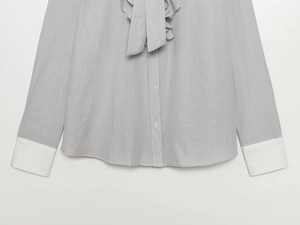 Detail of striped shirt with ruffled bow tie neckline and contrasting white cuffs