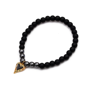 Handmade bracelet with black matte beads and rainbow zircon heart charm on white background