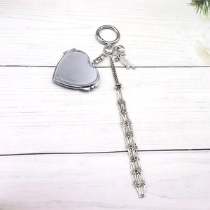 Porte-clés miroir cœur en métal argenté avec nœud rose et franges sur bois blanc