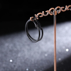 Detail view of large matte black hoop earrings displayed on a vintage metal jewelry stand