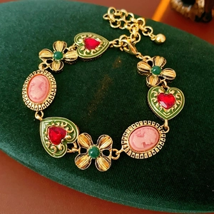 Détail d'un bracelet doré vintage avec gemmes cœur rouges et camées portrait sur velours