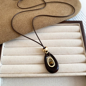 Detailed view of resin tiger eye oval pendant with brown wax cord on vintage fabric
