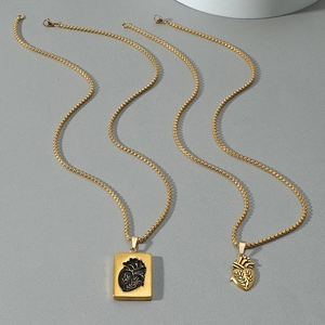 Collane con ciondolo cuore anatomico dorato per coppie con catena box su sfondo grigio