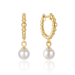 Macro shot of gold beaded hoop earrings with elegant hanging white round pearls
