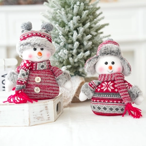 Detailed view of two Christmas plush snowmen in red and white knitting on wood stand