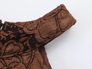 Gros plan sur la bretelle brodée marron d'une robe licou montrant les détails du tissu