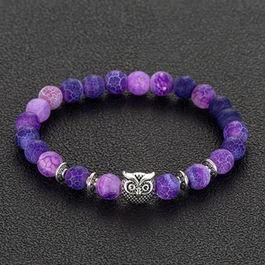 Macro shot of purple striped agate beads and silver owl charm on a beaded bracelet