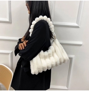 White plush shoulder bag with striped texture shown by a model in a black blazer