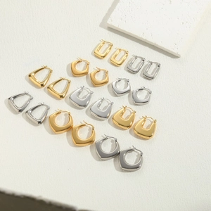 Collection of geometric gold and silver plated earrings on white textured background