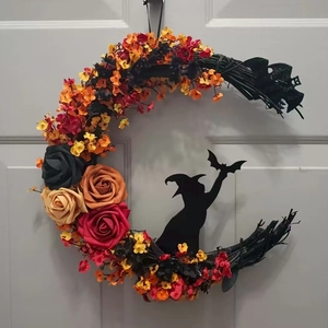 Detail of crescent moon wreath with black branches, roses, and a wizard silhouette on a door