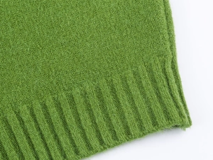 Vista macro del tessuto a maglia verde con texture morbida e polsini a costine sulla giacca
