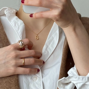Detail of 925 silver gold-plated S-letter necklace with bamboo texture and rings