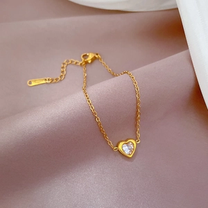 Close-up of gold heart bracelet with clear zircon on soft lavender silk background