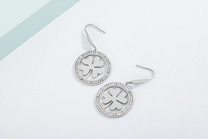 Detailed view of silver clover earrings with sparkling rhinestones in a circular frame